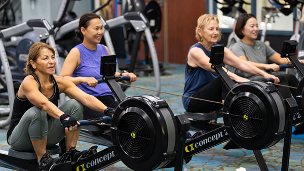 Four women exercising on rowing machines.