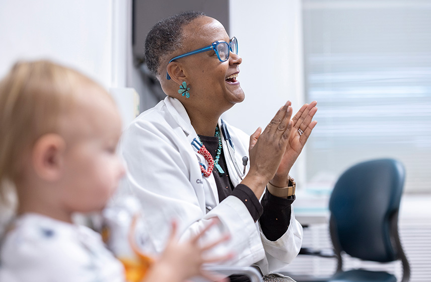 A Cleveland Clinic caregiver clapping with a child patient (front and out of focus).