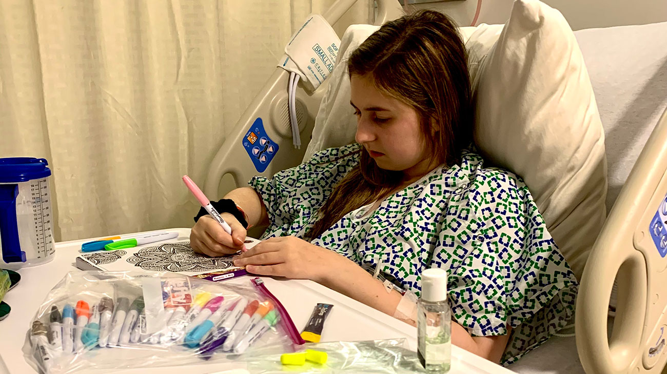 patient coloring with markers while lying in hospital bed