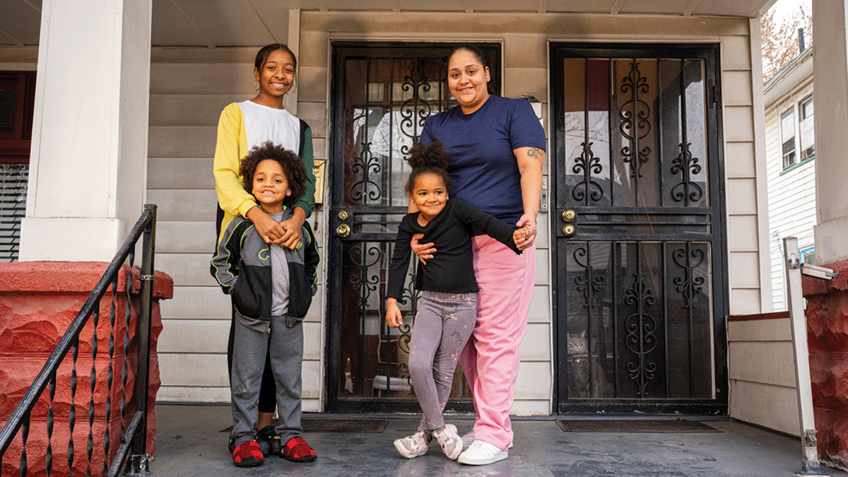 Family with young children pictured on the front porch of their house.