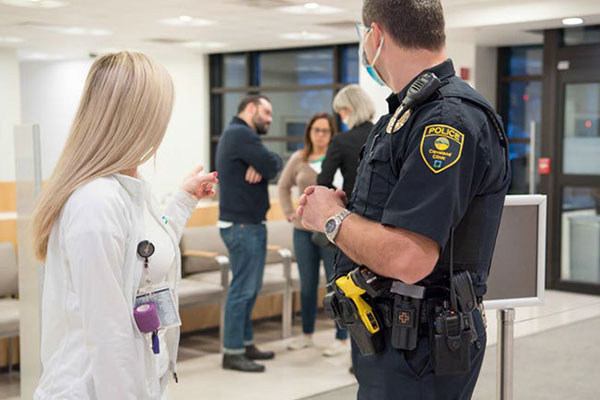 A Cleveland Clinic police officer talking with a caregiver pointing to people in the background.