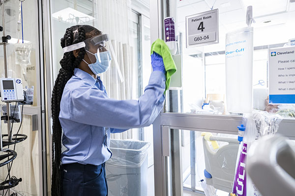 Caregiver wiping down the exterior glass of a patient room.