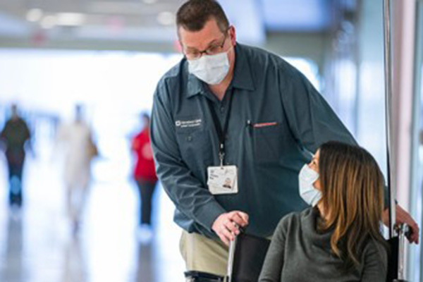 A Cleveland Clinic caregiver wheeling a patient.