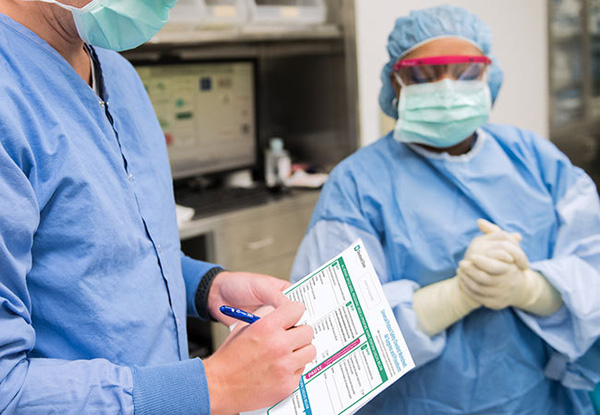 Two caregivers in scrubs checking items off a list