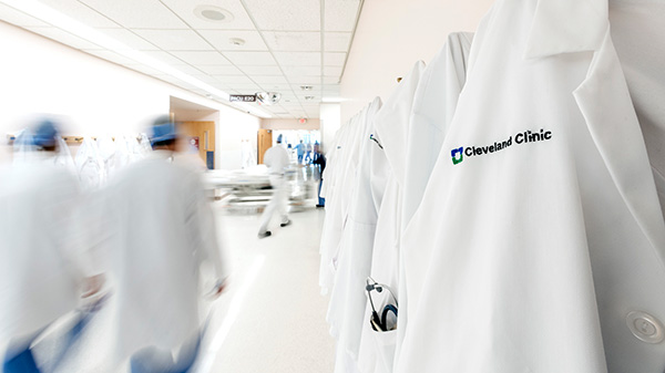 Caregivers in scrubs and white lab coats walking down a hallway