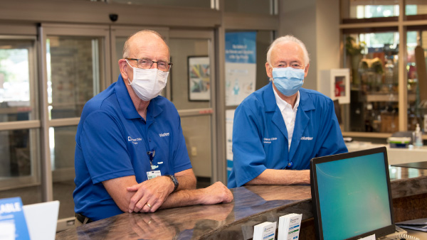 Volunteers with PPE standing in hospital lobby.