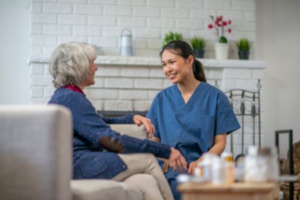 Home aid assisting an elderly patient with medications.