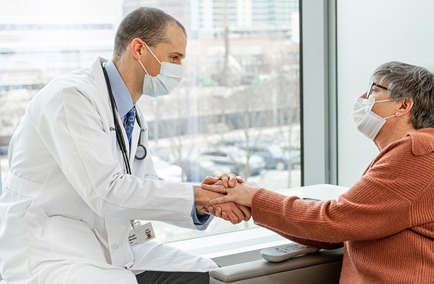 Cleveland Clinic doctor holding the hand of a patient while having a conversation.
