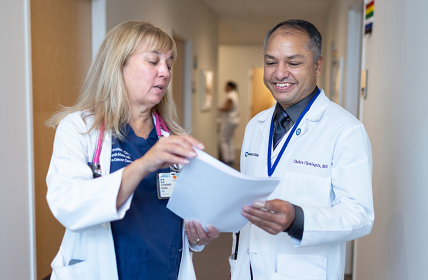 Two Cleveland Clinic caregivers looking at a sheet of paper having a conversations.