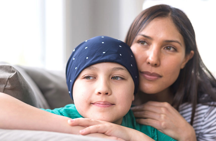 Mother hugging on her child, covering her shaved head due to cancer treatment.