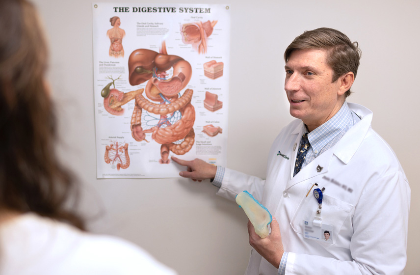 A Cleveland Clinic doctor pointing at a poster of the digestive system