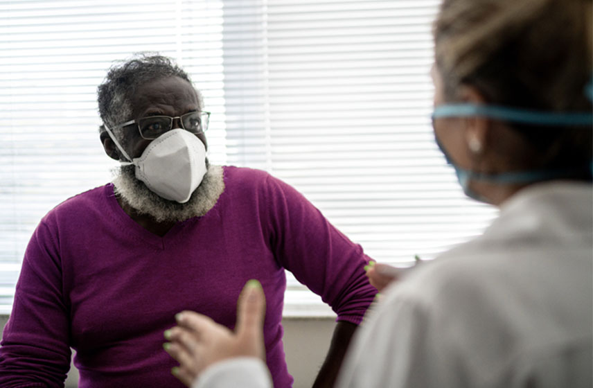A patient wearing an N95 mask talking to a Cleveland Clinic caregiver.