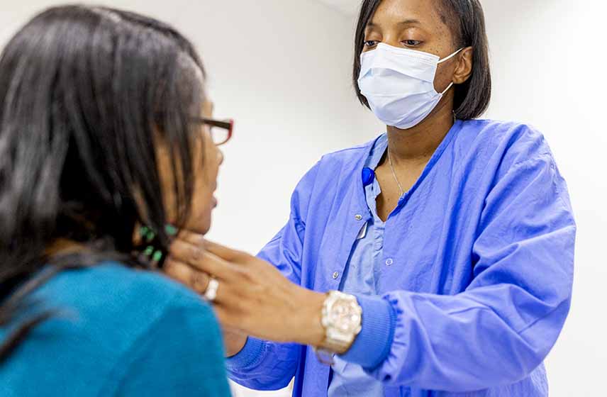 A patient having their throat examined by a nurse.
