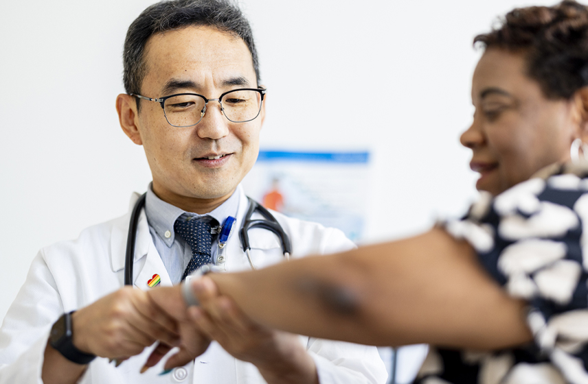 A caregiver examining a woman's arm.