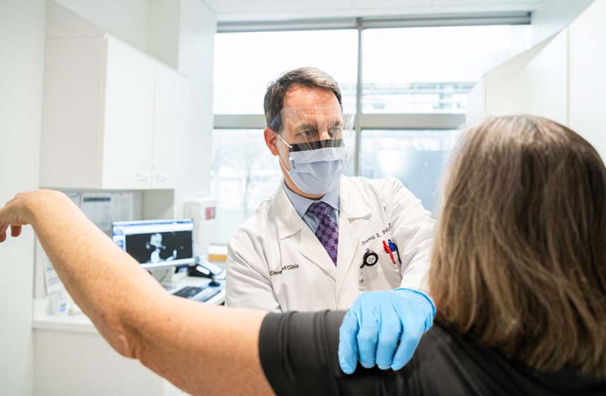 Cleveland Clinic doctor examining a patient's arm and shoulder.