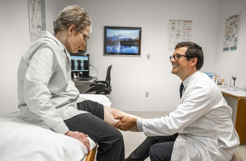 Doctor speaking with and examining a woman's knee prior to surgery.