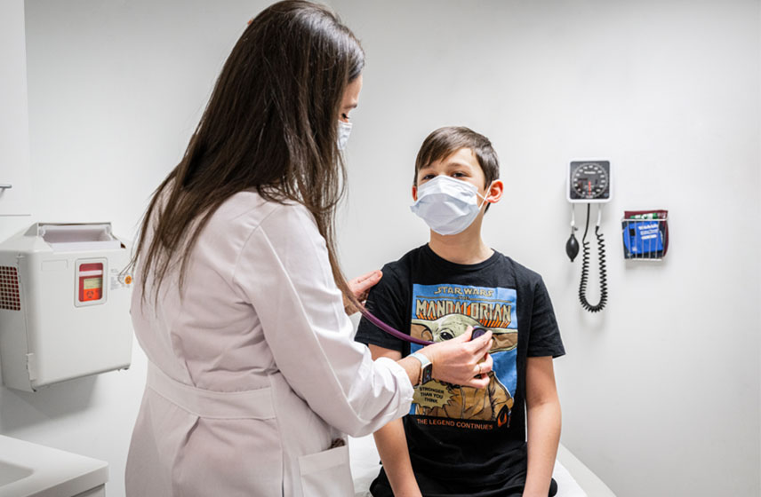 Cleveland Clinic Children's doctor examining a child patient, listening for his breath with a stethoscope.