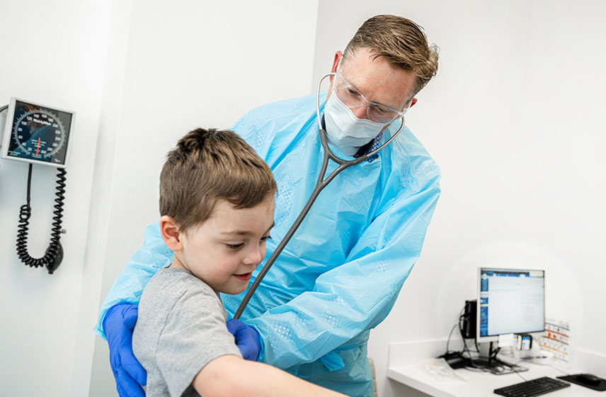 Cleveland Clinic doctor examining breath sounds of a young boy.