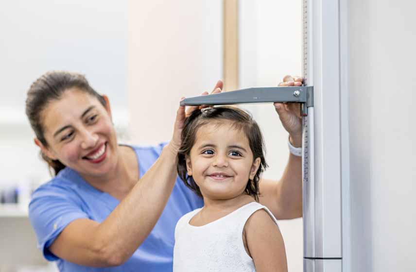 Nurse measuring young girl's height on a scale.