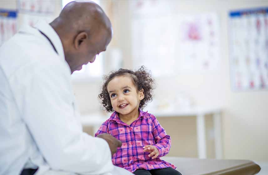 Cleveland Clinic Children's doctor speaking with young girl, with a big smile on her face.