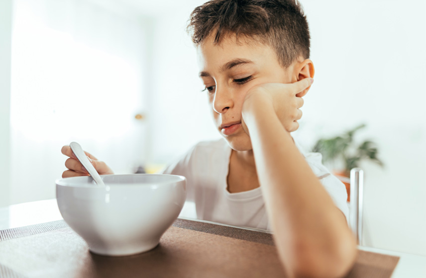 Child struggling to eat bowl of food due to Eosinophilic Esophagitis.