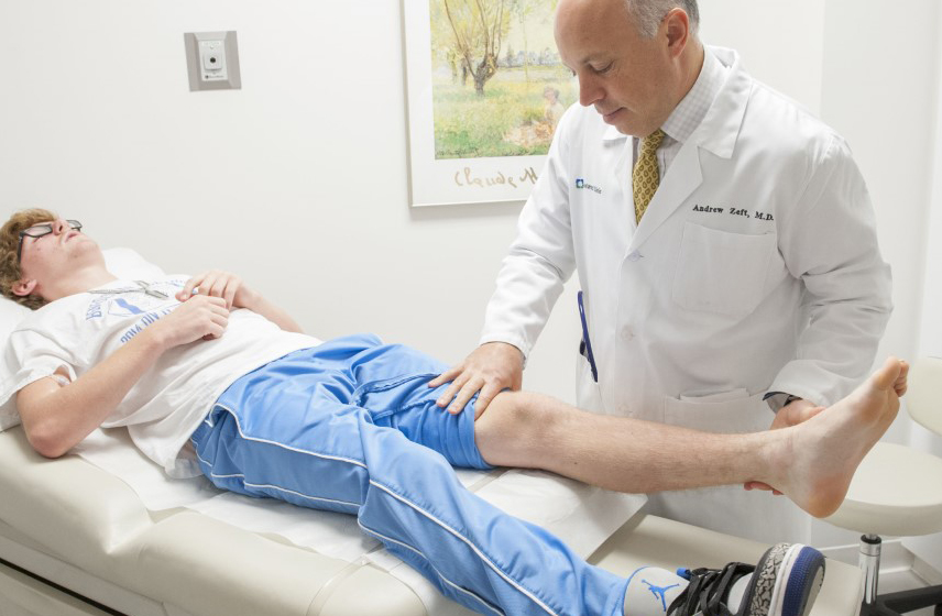 A Cleveland Clinic caregiver examining a teen's leg.