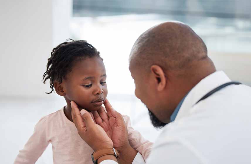 Male doctor examining young girl's face.