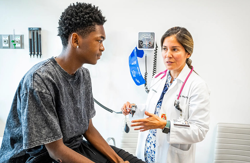 Cleveland Clinic doctor talking with teen boy in examination room.