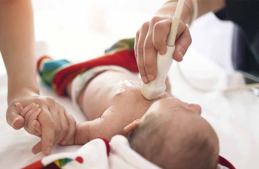 Healthcare providers performing an echocardiogram on a newborn.