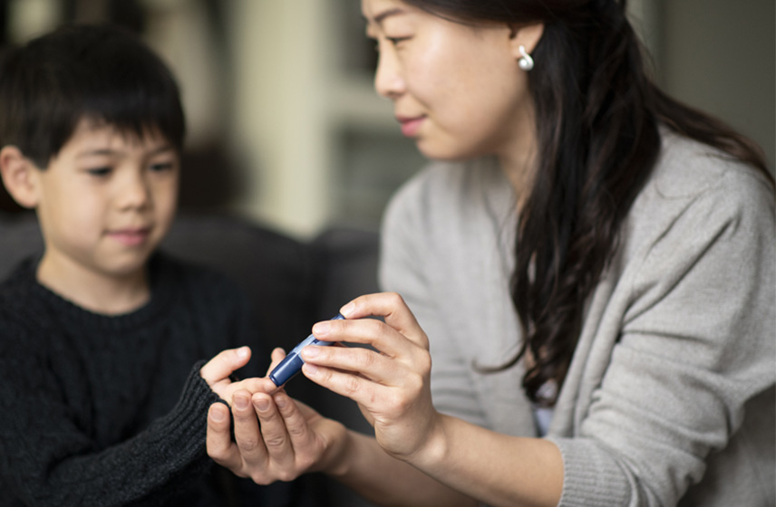 Woman teaching child with Type-1 Diabetes how to perform a blood glucose test.