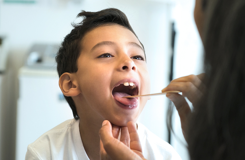 Child sticking their tongue out getting their throat looked at by a Cleveland Clinic doctor.