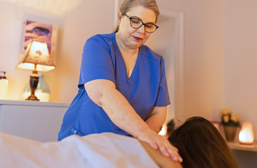 Massage therapist relieving tension in the upper back and shoulders of a patient.