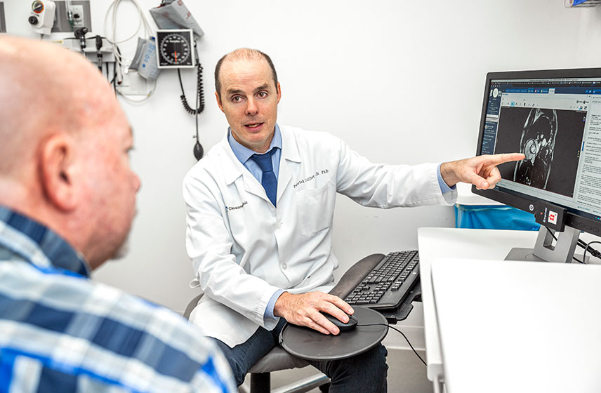 Doctor speaking to patient and pointing to scan on computer screen.
