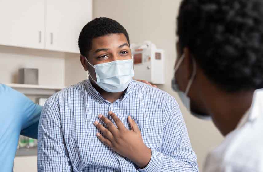 Male patient wearing face mask speaking with doctor.
