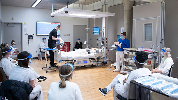 Instructor and students with simulator in educational setting.