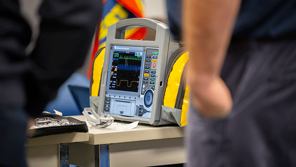 Cardiac monitor and defibrillator on a table during emergency medical training or response preparation.