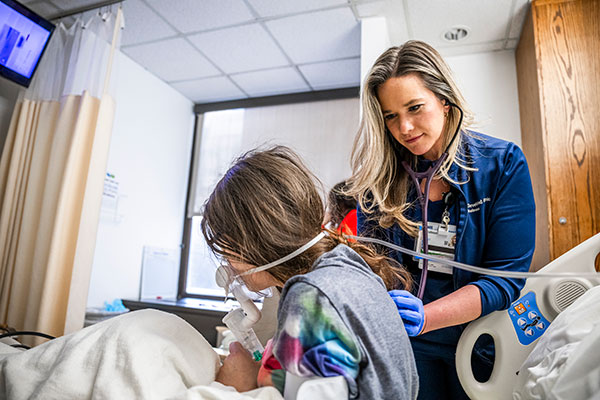 ED nurse assisting young girl with respiratory breathing treatment.