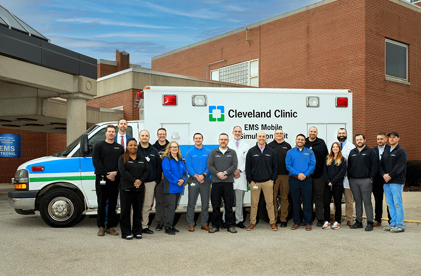Cleveland Clinic EMS mobile simulation unit parked outside a hospital entrance with EMS staff gathered around it.