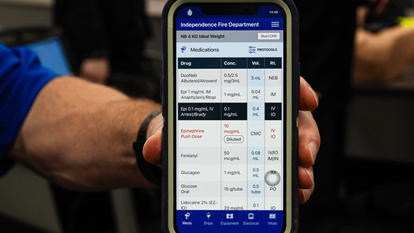 Smartphone displaying pediatric emergency medication dosing guidelines during a medical training scenario.