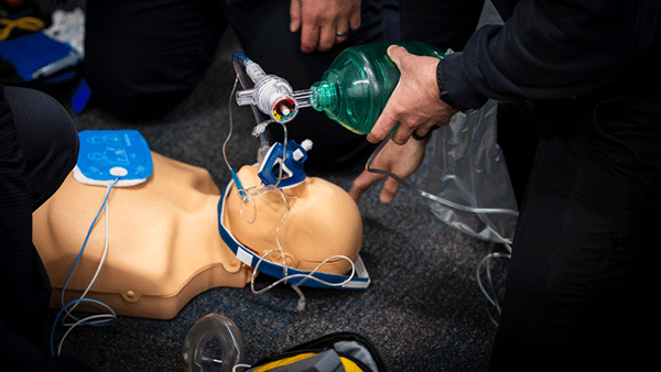 CPR training mannequin receiving bag-valve-mask ventilation during a medical emergency response exercise.