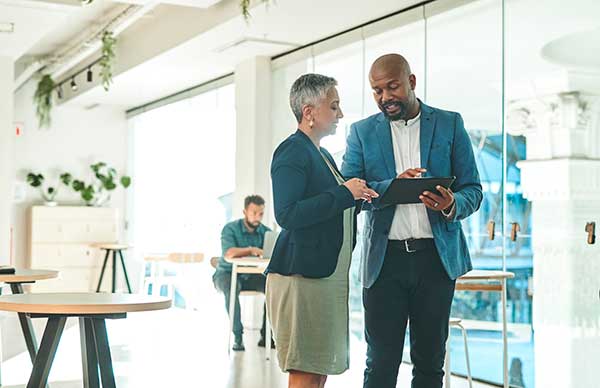 Two people talking in a hallway in business attire.