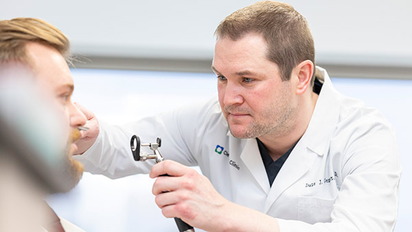 A plastic surgeon looking at a patient's nose