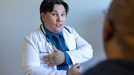 Caregiver in white coat speaking to patient.