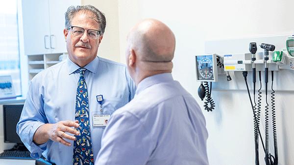 Patient and doctor discuss care in a medical office with diagnostic equipment.