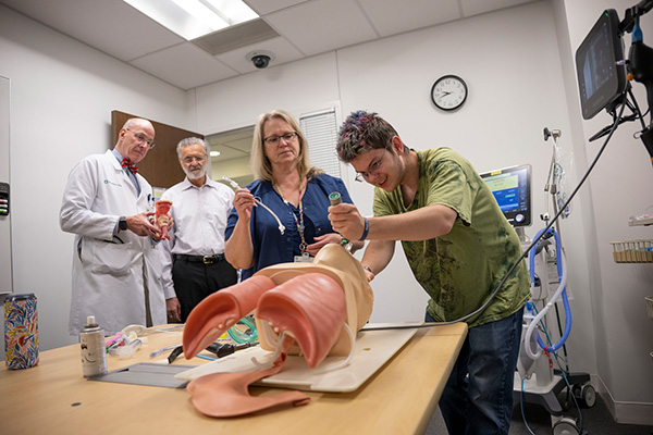 A student learning how to intubate a patient on a test dummy.
