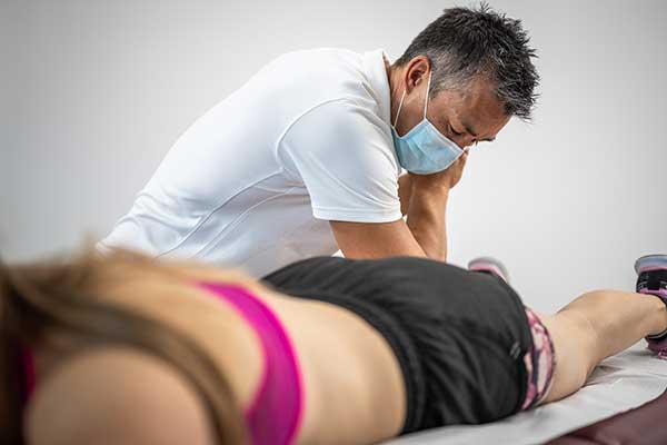 Male massage therapist massaging woman's leg.