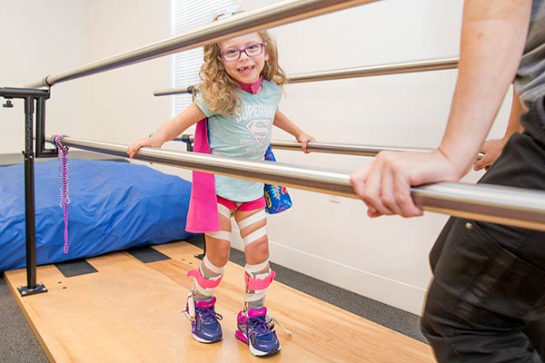 Little girl with leg braces practicing to walk