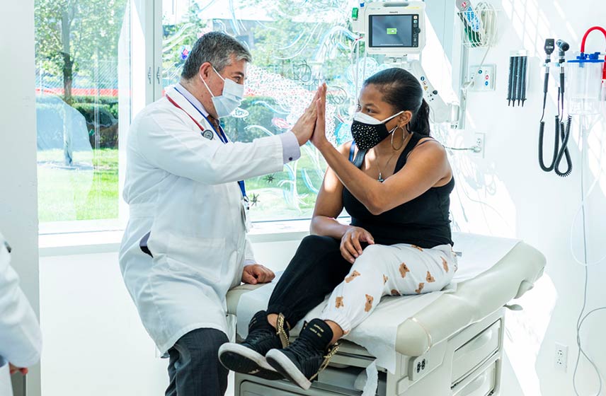 Physician and patient high-fiving in an exam room.