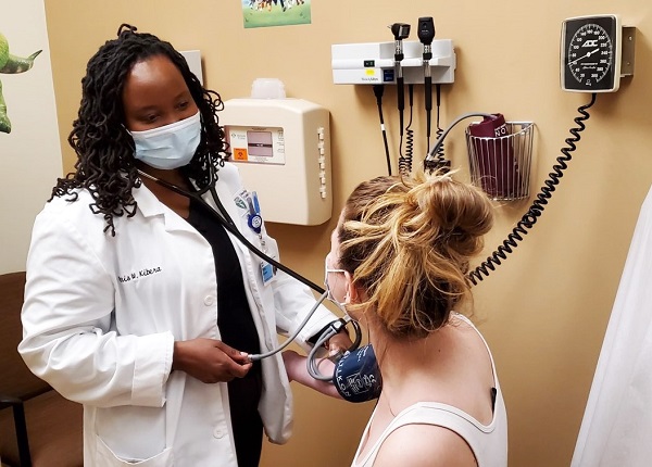TCC student Peris Kibera examines a patient at Cleveland Clinic Akron General