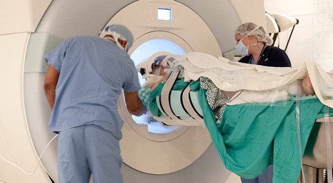 Patient rests on MRI bed, which slides in and out of the scanning area of the machine.